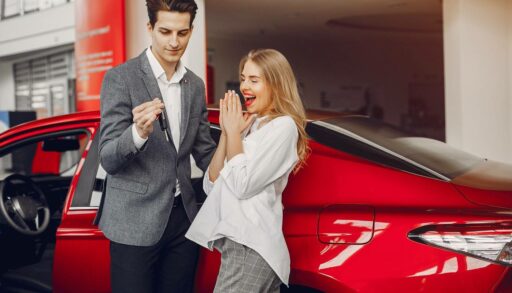 Молодой человек дарит девушке красный автомобиль