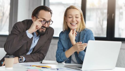 Коллеги улыбаются, глядя на монитор ноутбука