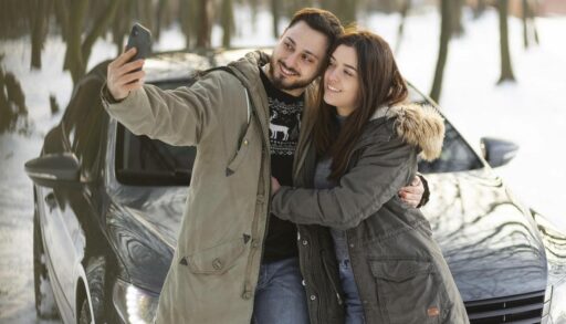 Пара делает селфи на фоне автомобиля