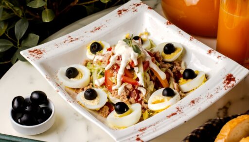 Праздничный салат с оливками и яйцами лежит в тарелке