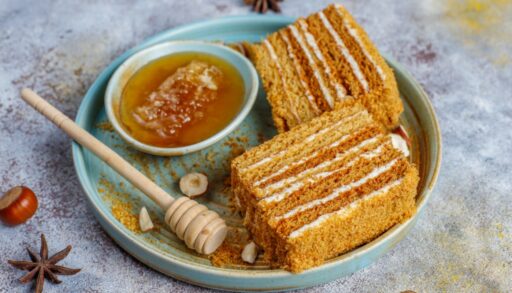 Торт медовик лежит на блюде рядом с медом в сотах