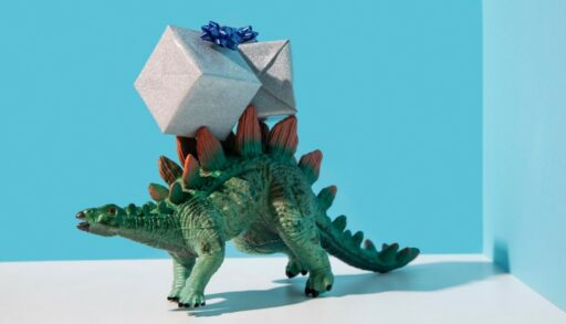 игрушечный динозавр тащит на спине подарки