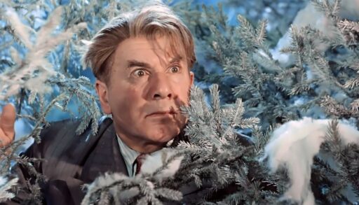 Мужчина выглядывает из-за елки