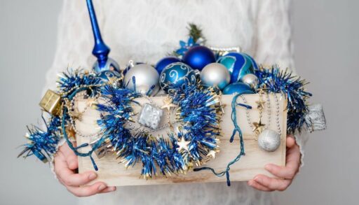 руки держат коробку с елочными игрушками