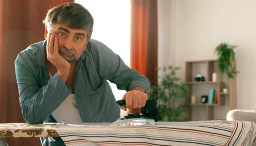 Задумчивый мужчина гладит рубашку