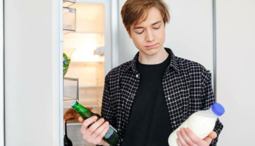 Молодой человек задумчиво стоит у холодильника