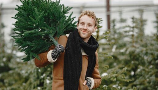 Улыбающийся мужчина несет елку