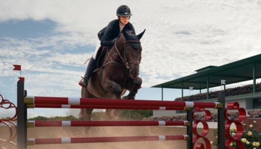 Девушка на лошади перепрыгивает через преграду