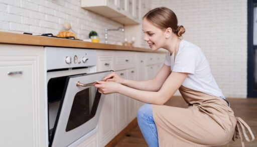 Девушка открывает дверцу духовки у плиты