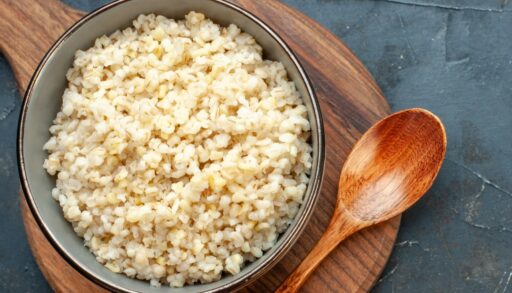 Перловая крупа в миске рядом с деревянной ложкой