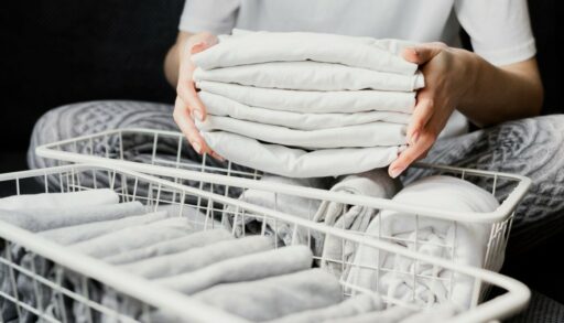 Руки держат чистое белье, полотенца