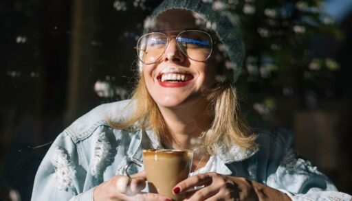 Смеющаяся молодая женщина с чашкой кофе