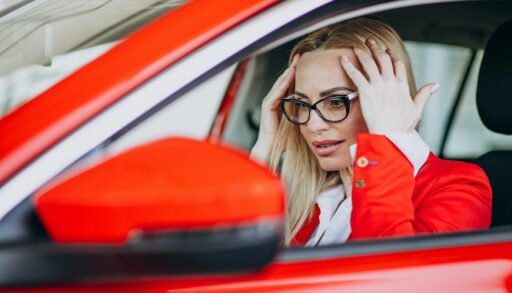 Привлекательная блондинка сидит в красной машине