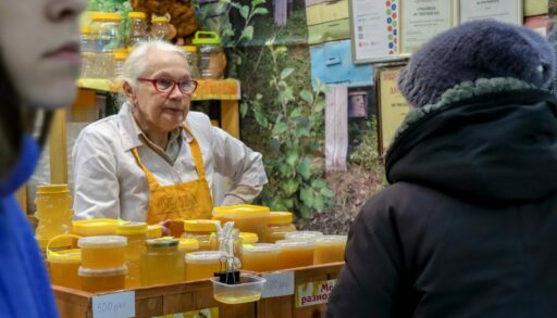 Пожилая женщина продает мед