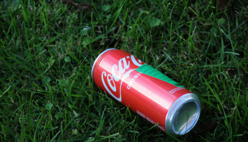 Банка Coca-Cola лежит на траве