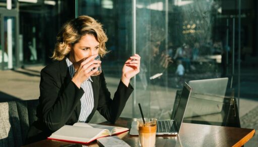 Деловая женщина пьет воду, глядя в ноутбук