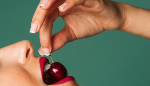 рука с нежным маникюром держит вишню