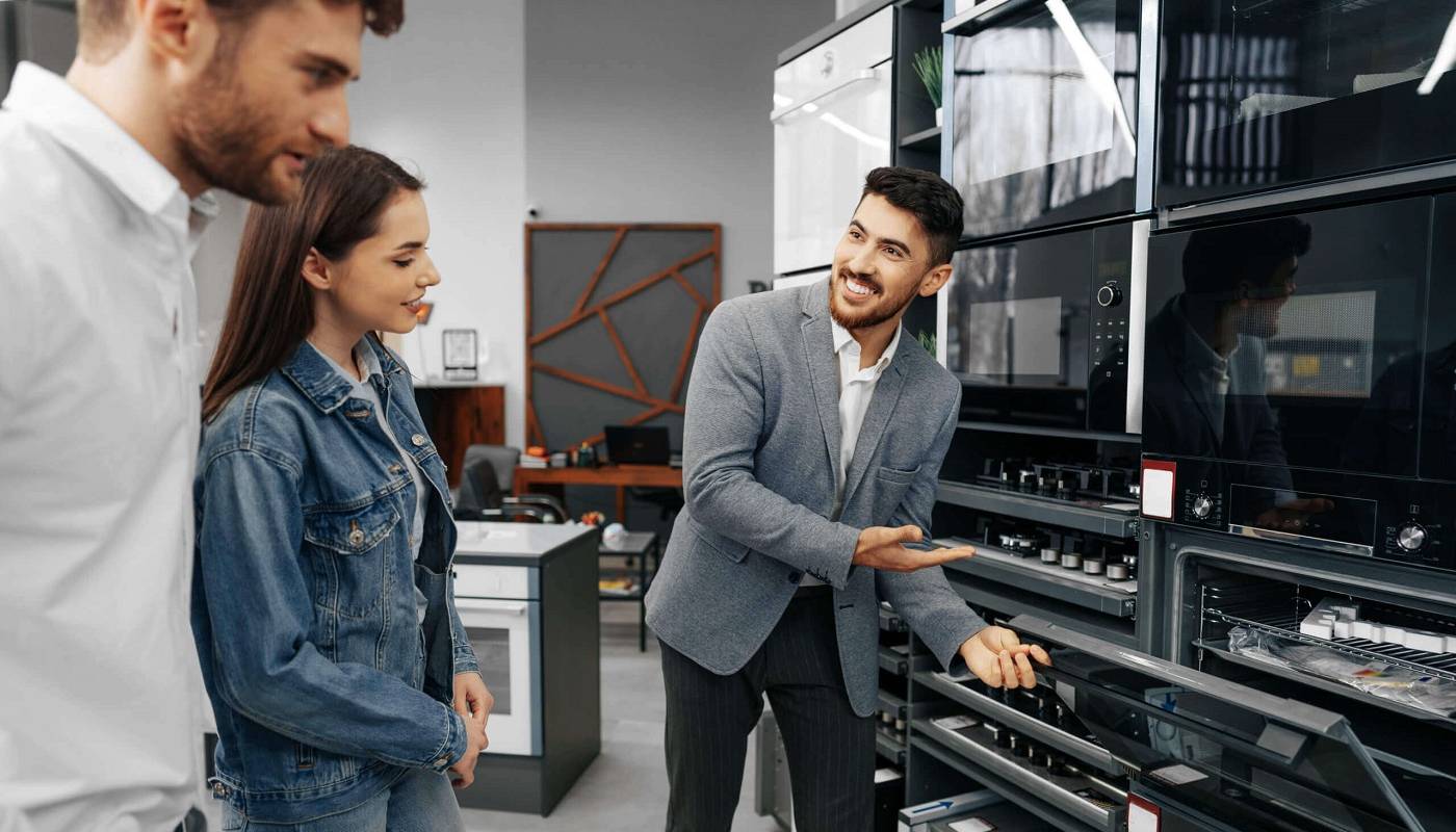 Продавец-консультант помогает молодой паре выбрать бытовую технику