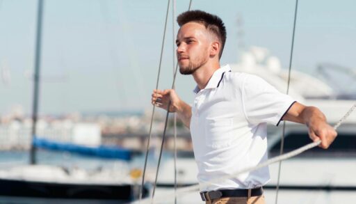 Молодой человек стоит на палубе яхты