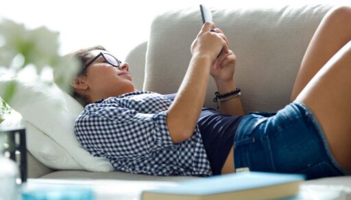 Красивая девушка. лежа на диване, разговаривает по телефону