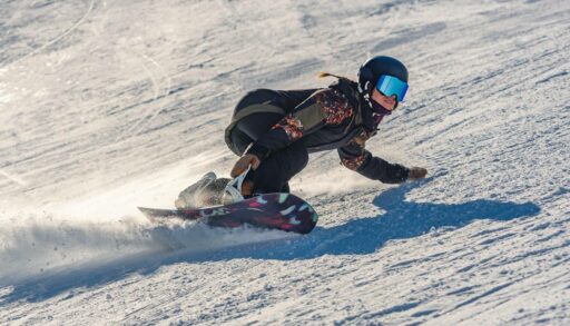Сноубордист делает вираж на крутом горном склоне