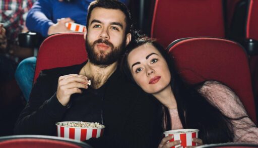 Пара в кинотеатре смотрит фильм и ест попкорн