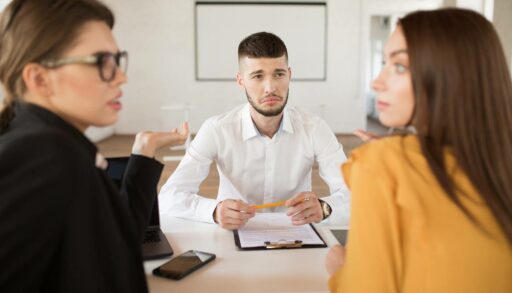 Расстроенный молодой мужчина в белой рубашке смотрит на двух девушек