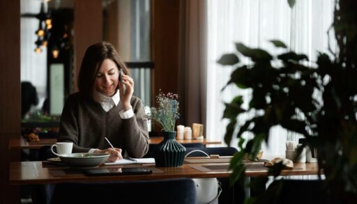 Деловая женщина общается по телефону, сидя в кафе