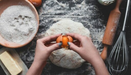 женщина разбивает яйца для праздничной выпечки