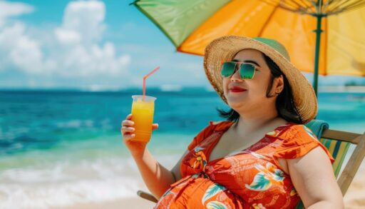 Полная женщина пьет коктейль, сидя в шезлонге на берегу моря