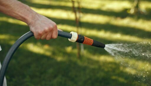 рука держит поливочный шланг