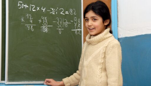 Девочка у школьной доски решает задачу по математике