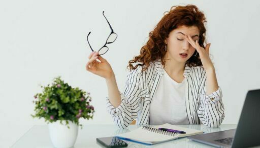 Уставшая девушка закрыла глаза, чтобы отдохнуть от работы за ноутбуком