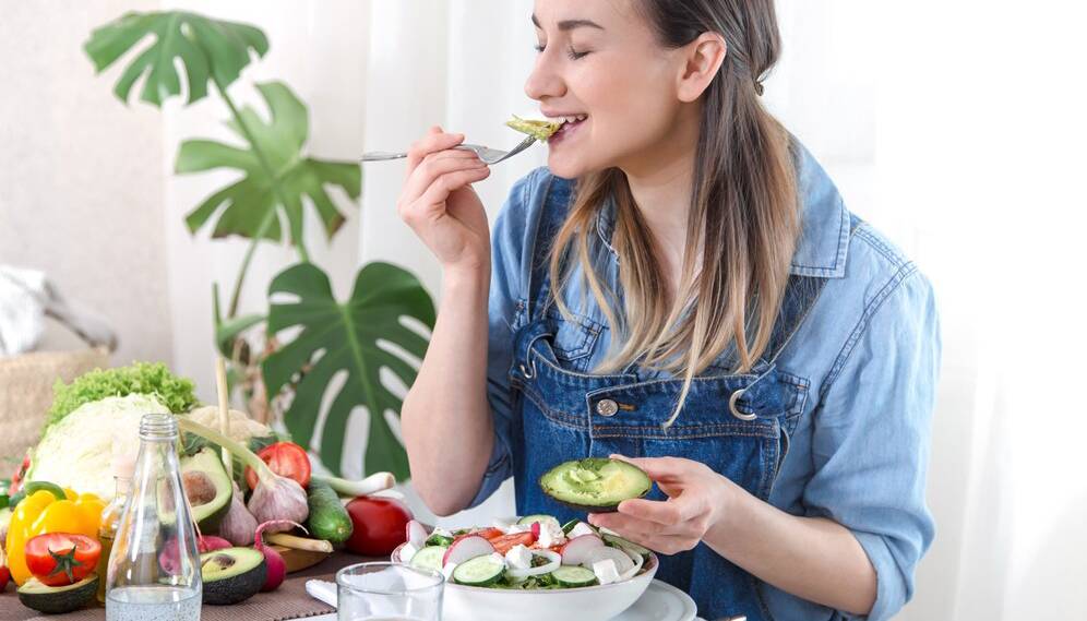 young-happy-woman-eating-salad-table_169016-6396