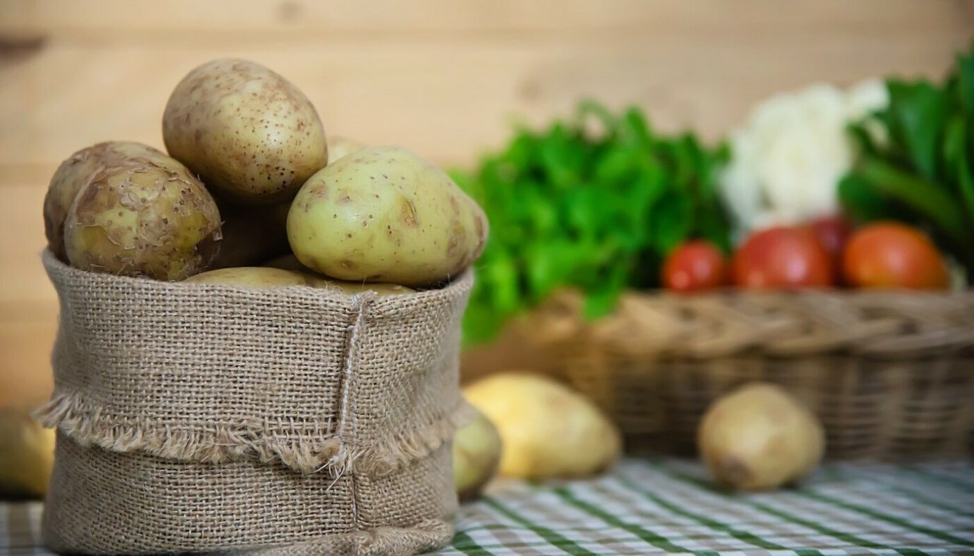 На переднем плане - мешочек с картошкой, на заднем - другие овощи