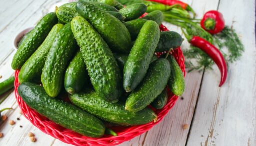 огурцы и острый красный перец в плетеной корзинке на столе